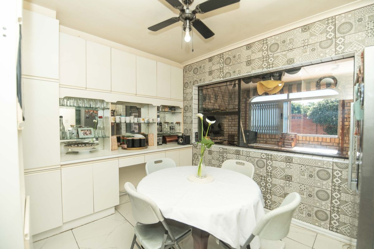 A functional kitchen area featuring built-in cabinetry, decorative tiled walls, and a ceiling fan, offering a practical space for dining and meal preparation.