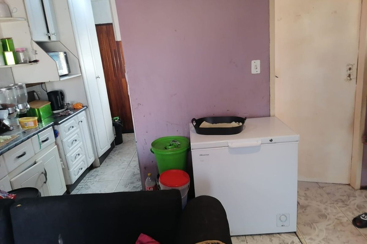 A functional kitchen area featuring built-in cabinetry and tiled flooring, currently showing signs of wear and requiring cosmetic updates to improve the space.