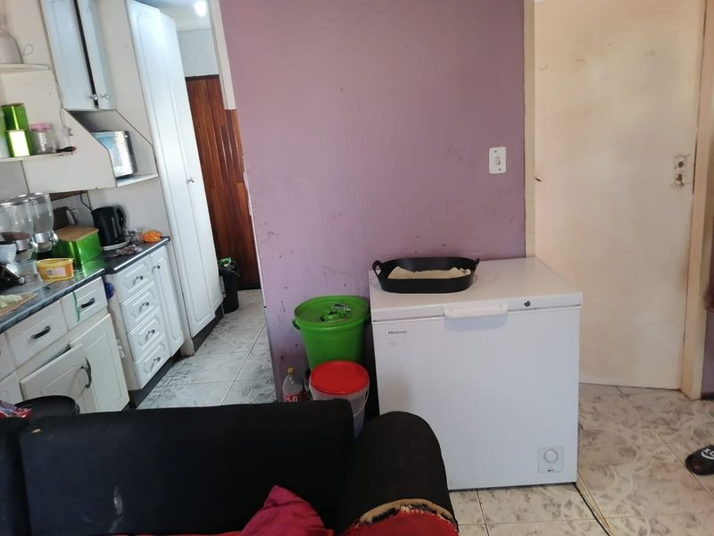 A functional kitchen area featuring built-in cabinetry and tiled flooring, currently showing signs of wear and requiring cosmetic updates to improve the space.