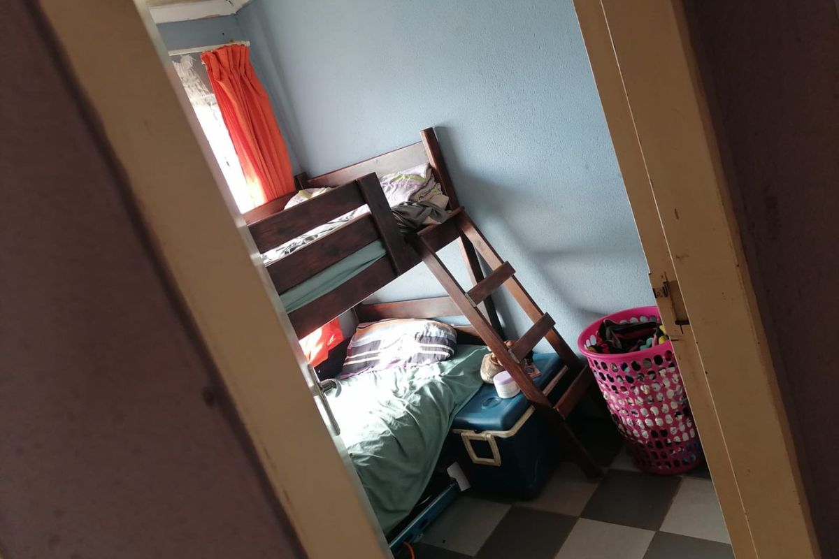 A bedroom featuring tiled flooring and visible signs of ceiling water damage and paint deterioration.