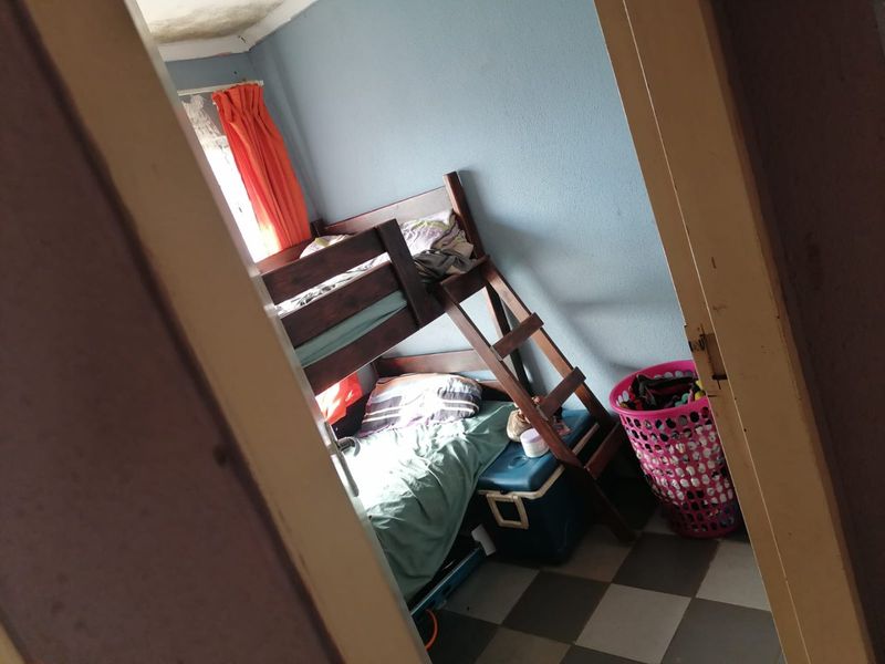 A bedroom featuring tiled flooring and visible signs of ceiling water damage and paint deterioration.