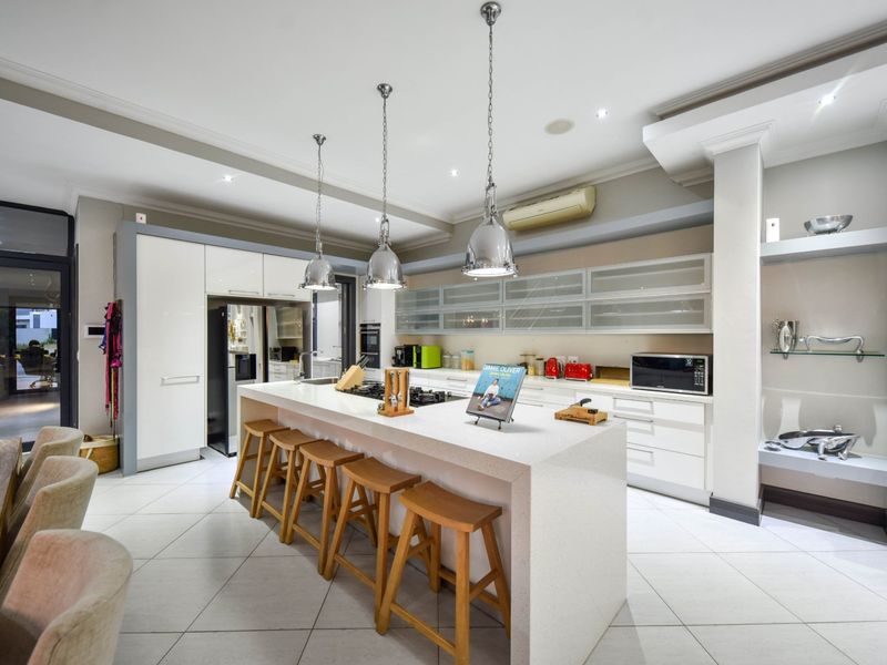 Modern kitchen featuring a large central island with quartz countertops, built-in appliances, sleek cabinetry, and stylish pendant lighting in an open-plan layout.