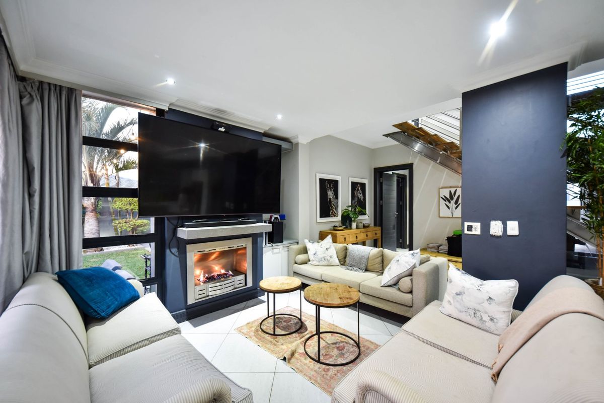 Modern living room featuring a built-in fireplace, tiled flooring, and an open staircase, creating a bright and contemporary atmosphere.