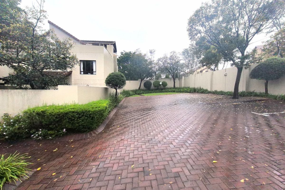 A spacious paved rear courtyard area featuring a boundary wall and established garden trees, providing a private outdoor space.