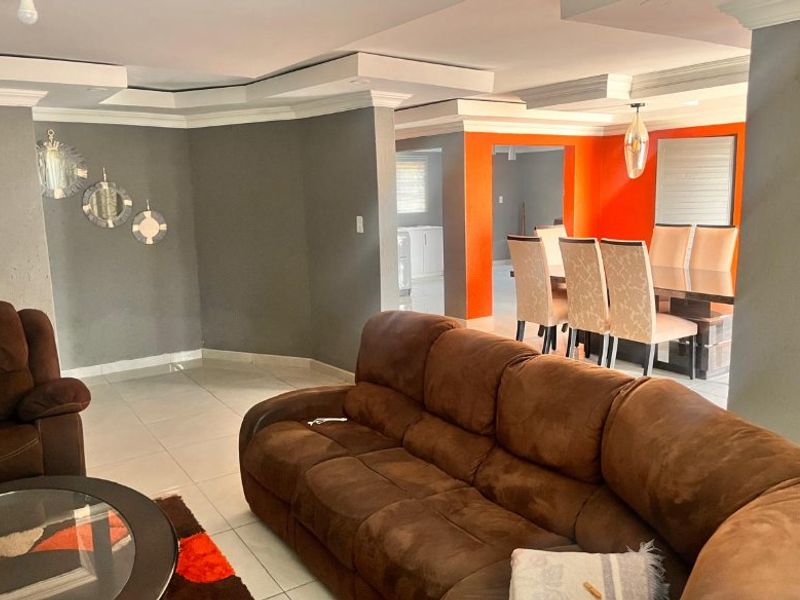 Open plan living and dining area featuring tiled flooring, recessed ceiling details, and a distinct color-blocked wall design.