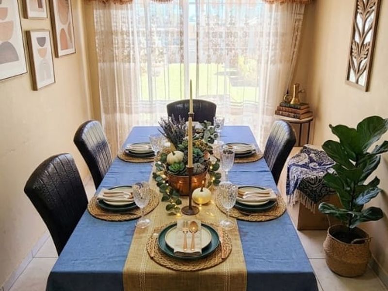 A formal dining room featuring tiled flooring, a ceiling fan, and a sliding glass door providing natural light and garden access.