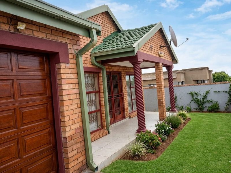 Well-maintained face brick home featuring a covered porch with decorative columns, a secure garage, and a neat front garden.