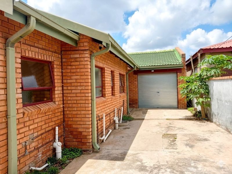 Rear exterior view of the property featuring a face brick facade, concrete driveway, and a secure roller shutter garage door.