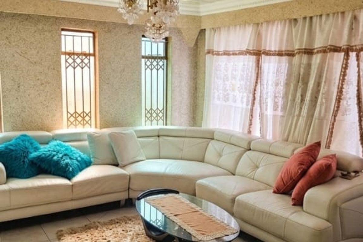 A living room featuring a decorative ceiling rose, recessed lighting, tiled flooring, and security grilles on the windows.