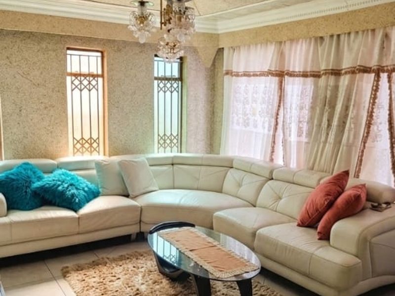 A living room featuring a decorative ceiling rose, recessed lighting, tiled flooring, and security grilles on the windows.