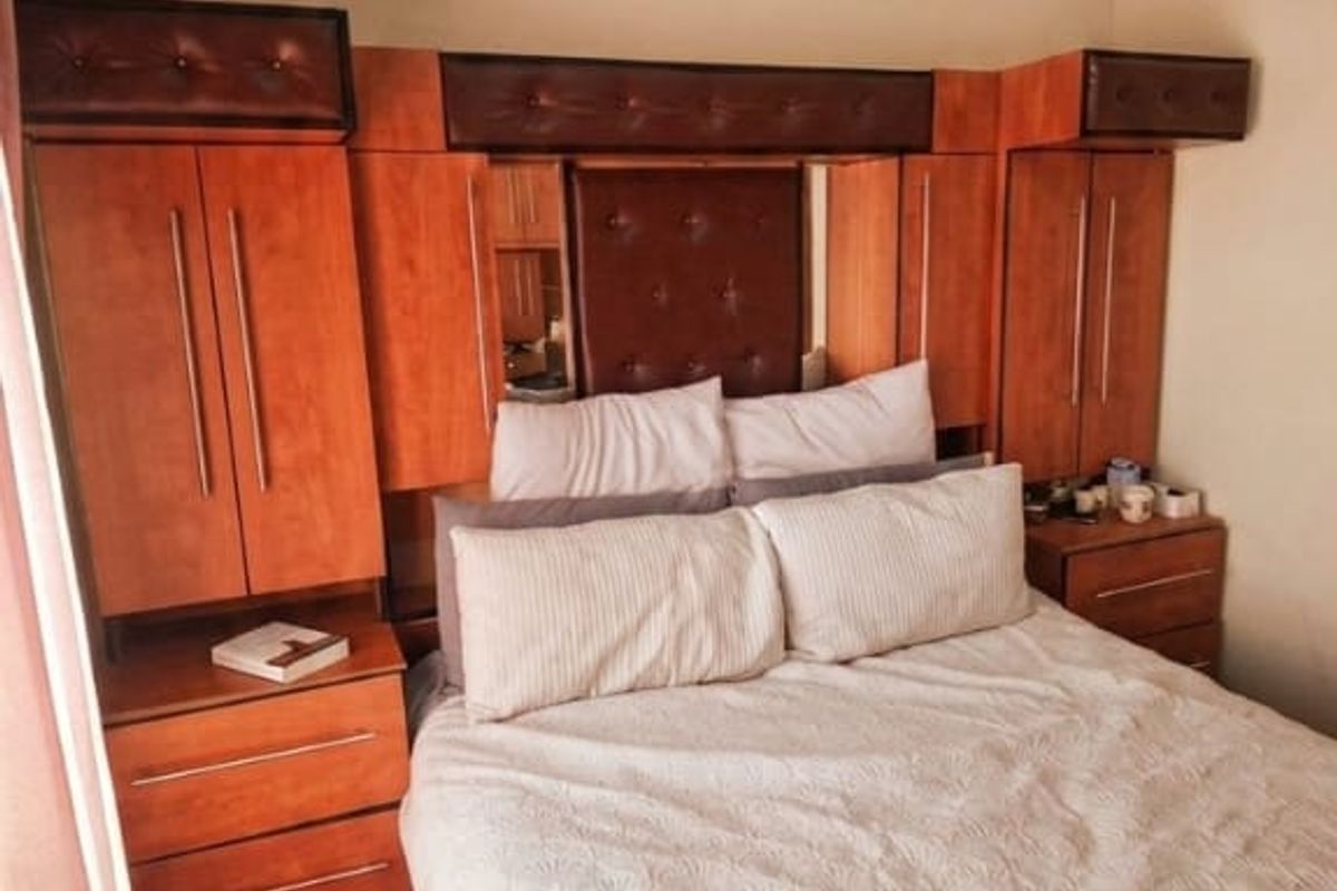 Bedroom featuring a large, integrated wooden headboard unit with built-in wardrobes and bedside storage cabinetry.