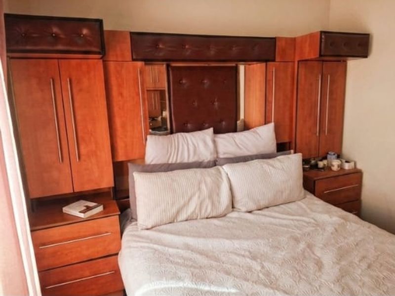 Bedroom featuring a large, integrated wooden headboard unit with built-in wardrobes and bedside storage cabinetry.
