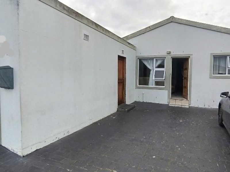 Front exterior view of the property featuring a paved driveway, garage access, and main entrance with aluminium window frames.