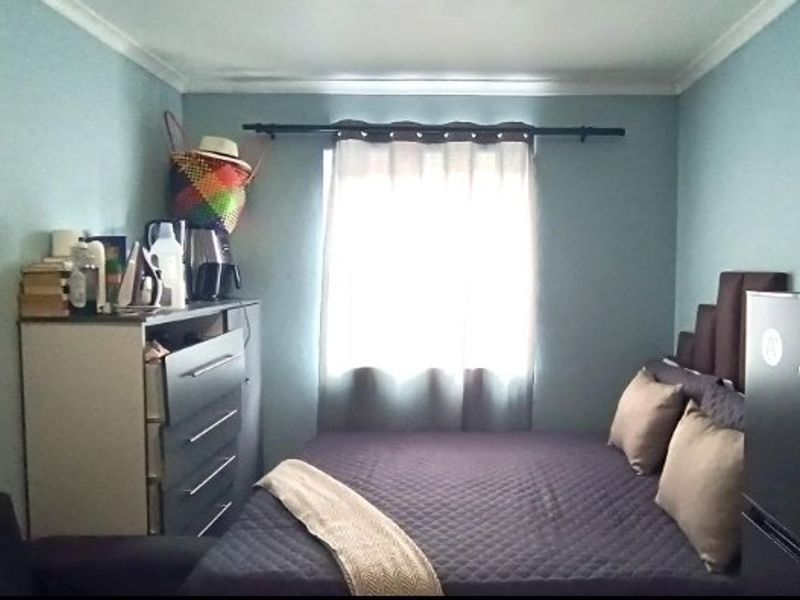 A standard bedroom featuring light blue walls, coving, and a window with a curtain rod.