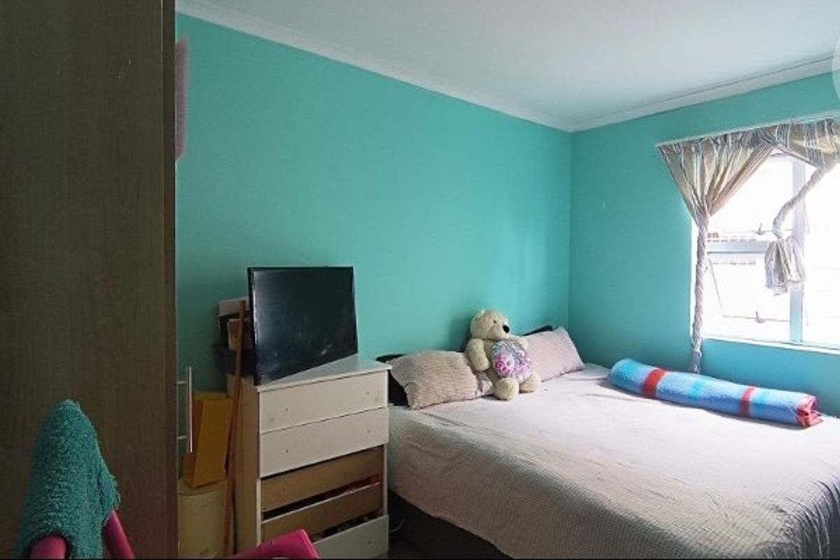 A standard bedroom featuring turquoise painted walls and a window with curtain tracks.