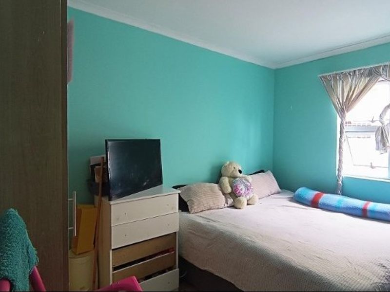 A standard bedroom featuring turquoise painted walls and a window with curtain tracks.