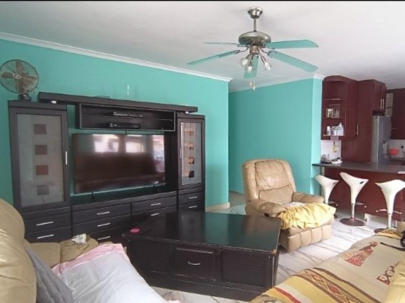 Open plan living and kitchen area featuring tiled flooring, a breakfast bar, and a ceiling fan.