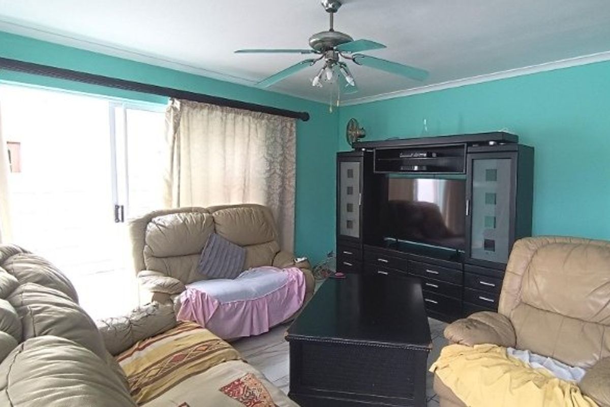 A living room featuring a ceiling fan, tiled flooring, and a large sliding glass door providing access to the exterior.