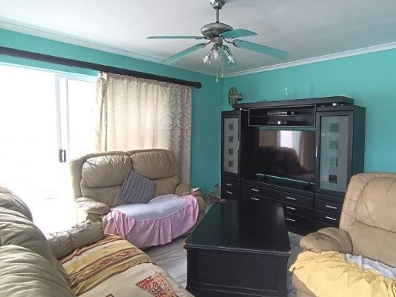 A living room featuring a ceiling fan, tiled flooring, and a large sliding glass door providing access to the exterior.