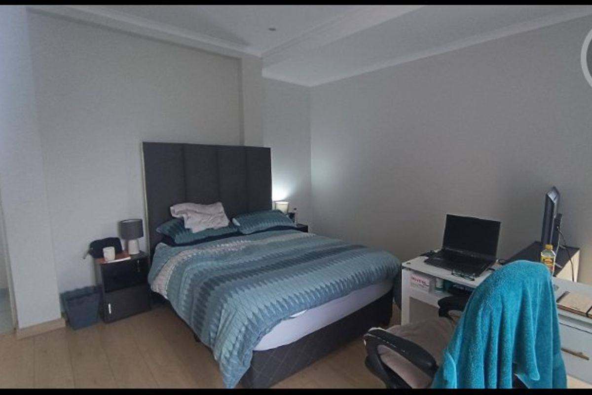 A functional bedroom featuring laminate flooring and cove ceiling detailing, providing a neutral base for personal styling.