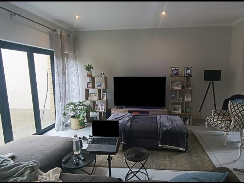 A comfortable living room featuring tiled flooring, recessed downlighting, and large sliding glass doors that provide direct access to the outdoor patio area.