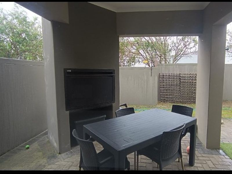 A covered patio area featuring a built-in braai and paved flooring, providing a functional outdoor entertainment space.