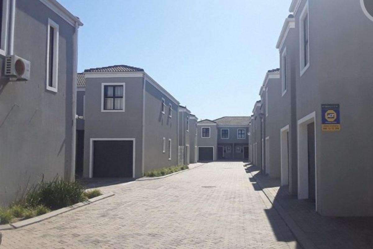 A view of the paved access road within a residential apartment complex, featuring multiple garage entrances and modern grey exterior facades.