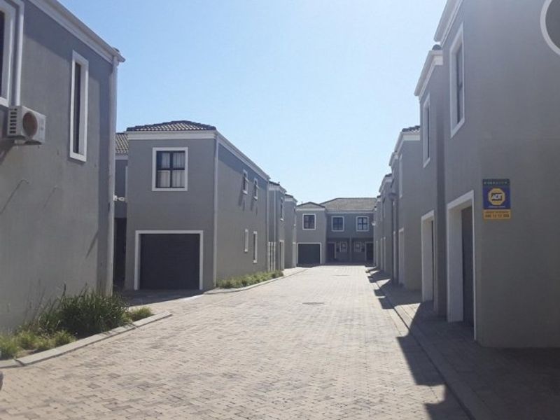 A view of the paved access road within a residential apartment complex, featuring multiple garage entrances and modern grey exterior facades.