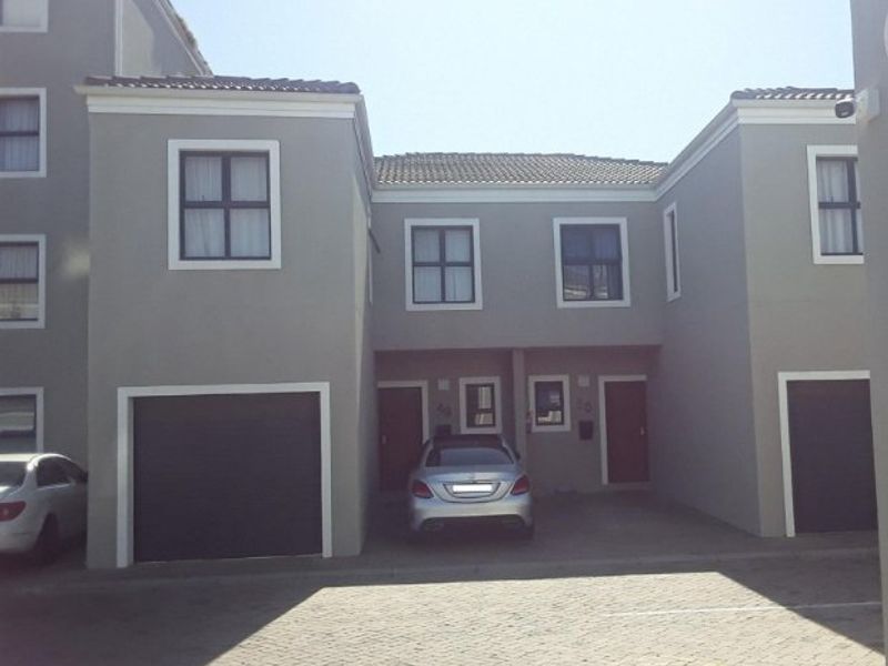 Front elevation of a modern apartment complex featuring paved driveway access, integrated garages, and neutral grey exterior finishes.