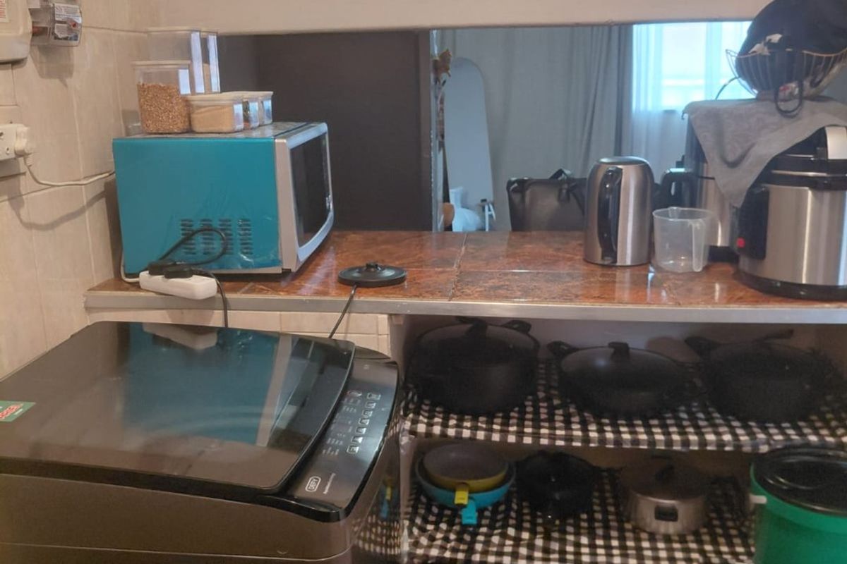 A compact kitchen area featuring tiled countertops and flooring, with built-in shelving and wall-mounted utility connections.