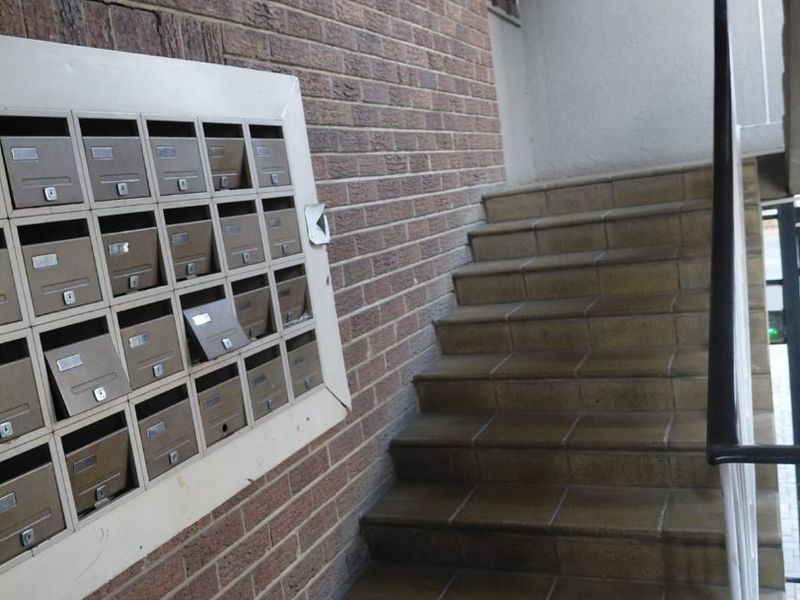 Entrance area featuring a brick wall with built-in mailboxes and a tiled staircase with a metal handrail.