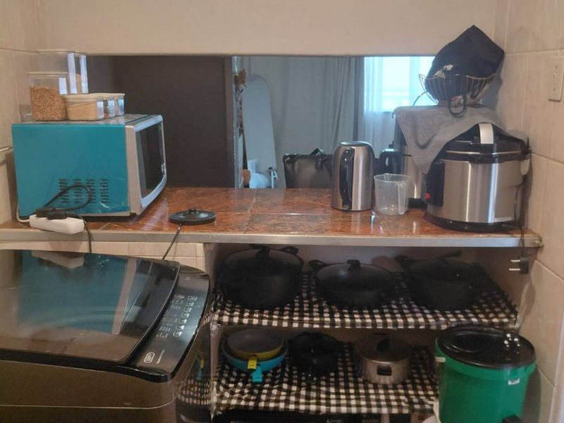 A compact scullery or utility area featuring tiled countertops, a tiled backsplash, and open shelving for storage.