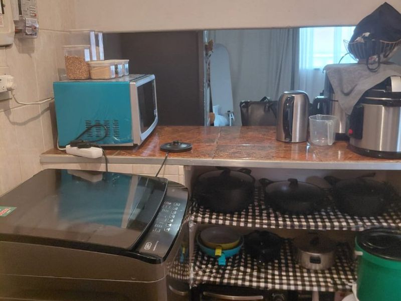 A compact laundry and utility area featuring tiled countertops, wall tiling, and floor tiles, providing functional space for appliances and storage.