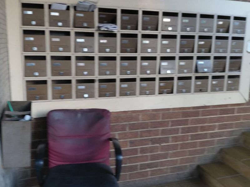 Entrance area featuring a wall-mounted bank of mailboxes, brick wall finish, and tiled flooring.