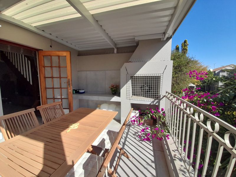 Covered patio area featuring a built-in braai, concrete prep surface, and metal balustrade, providing an ideal space for outdoor dining and entertainment.