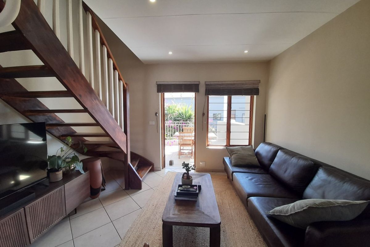 A living room featuring a timber staircase, tiled flooring, and direct access to an outdoor balcony area.