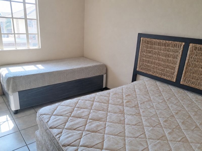 A bedroom featuring tiled flooring and a grid-pattern window, providing natural light to the space.