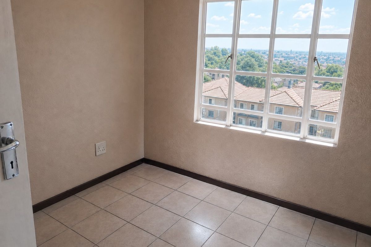 An empty bedroom featuring tiled flooring, a large multi-pane window with exterior views, and neutral wall finishes.