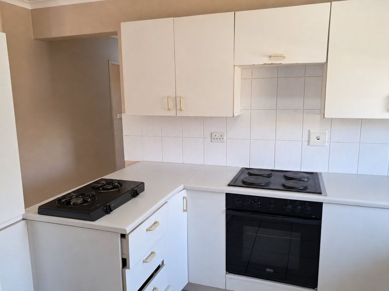 A functional kitchen featuring white cabinetry, tiled backsplash, and dual hob setup with a built-in electric oven.