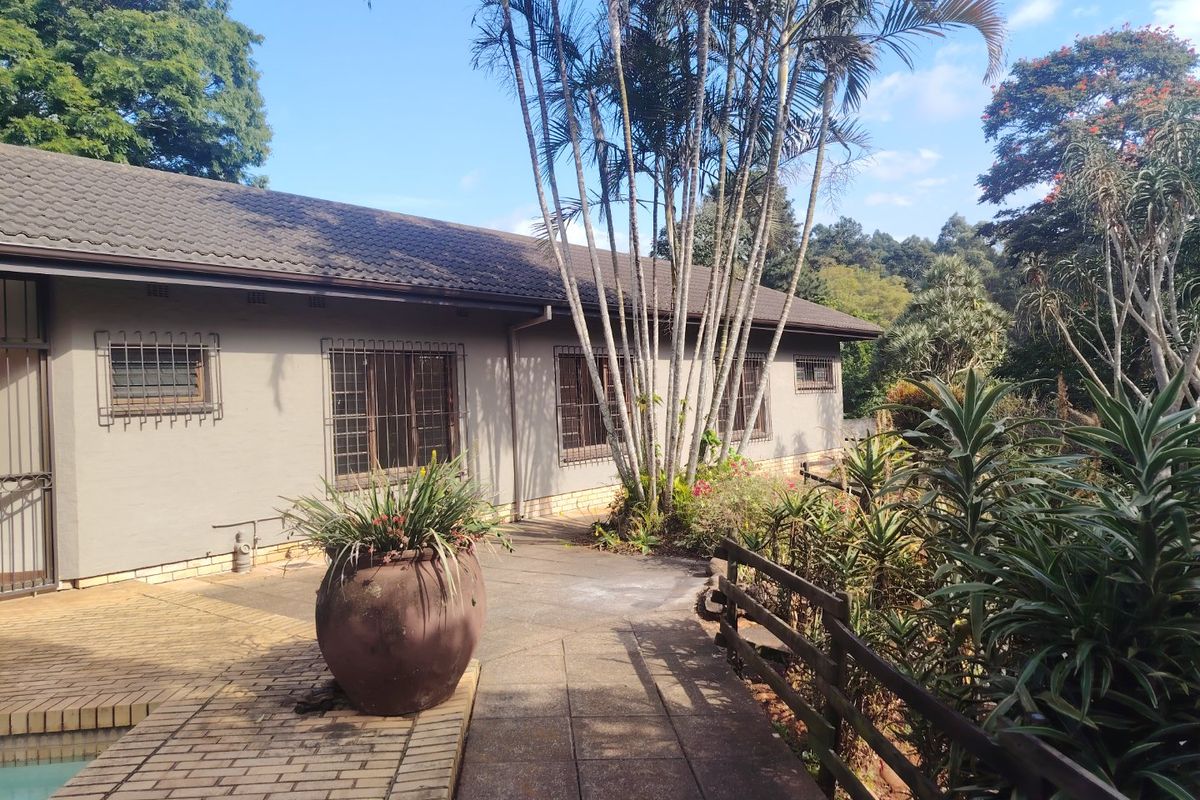 Rear exterior view of the house featuring a paved walkway, security bars on windows, and access to the pool area.