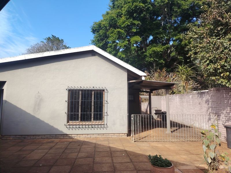 Rear view of the property featuring a paved patio area, covered outdoor space, and secure boundary walling.