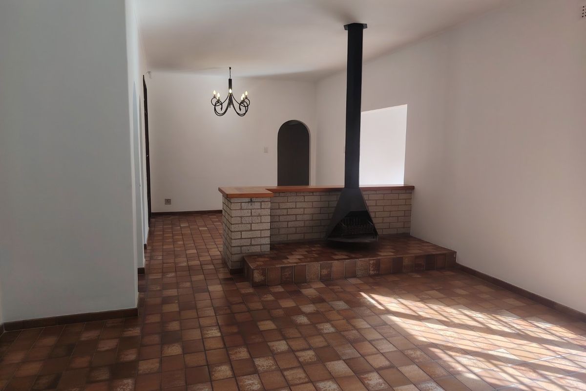Spacious living area featuring a central freestanding fireplace with a brick hearth and traditional tiled flooring throughout.