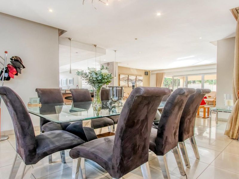 Spacious open-plan dining area featuring polished porcelain floor tiles, recessed downlighting, and seamless flow to the adjacent living space and outdoor patio.