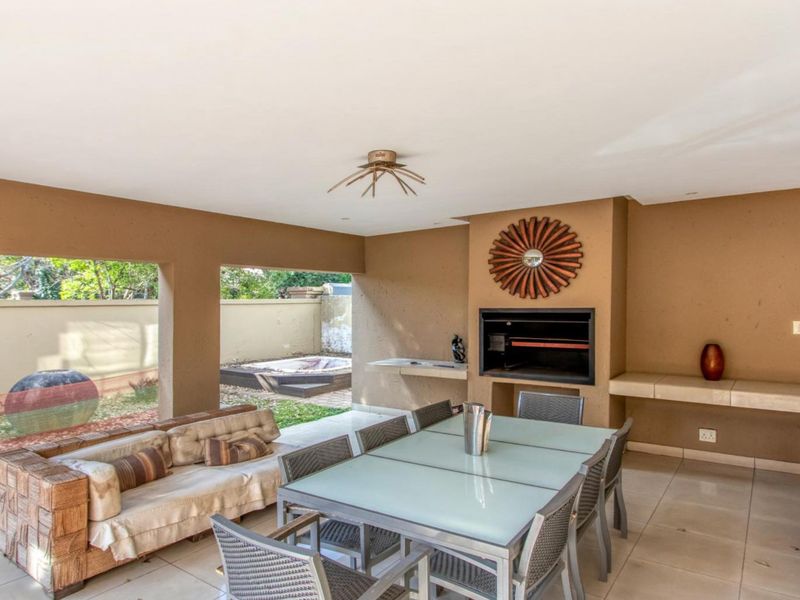 Covered patio area featuring a built-in braai, concrete shelving, and tiled flooring, providing a functional space for outdoor dining and entertainment.