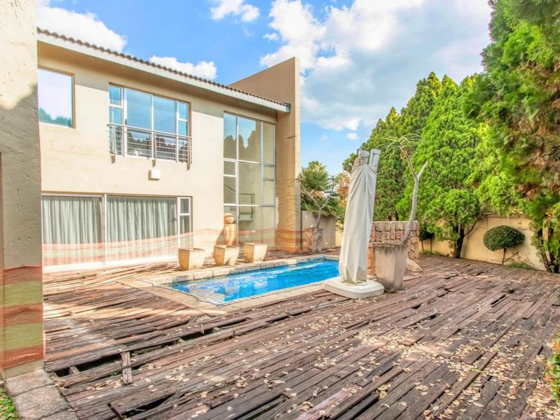 Rear exterior view featuring a swimming pool and extensive timber decking in need of significant repair and maintenance.