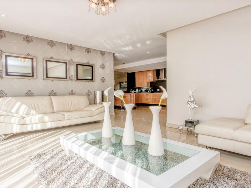 Spacious open-plan living area featuring tiled floors, recessed lighting, and a seamless transition into a well-appointed kitchen with built-in cabinetry.