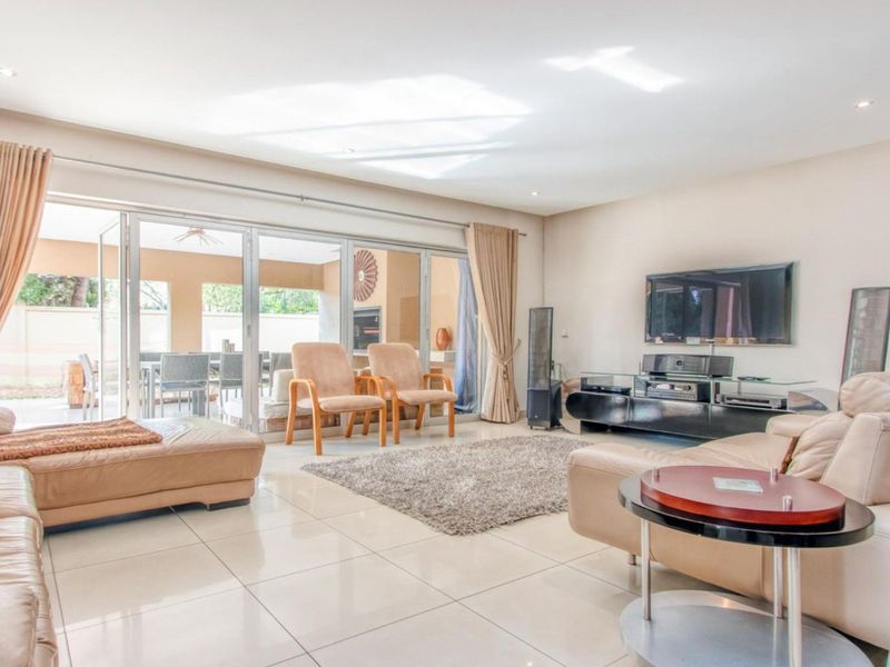 Spacious living room featuring large sliding glass doors that open to an outdoor patio, complemented by neutral tiled flooring and recessed lighting.