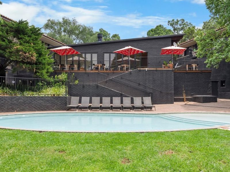 A well-maintained communal pool area featuring a paved deck, brick retaining walls, and a raised patio accessible via a metal staircase.
