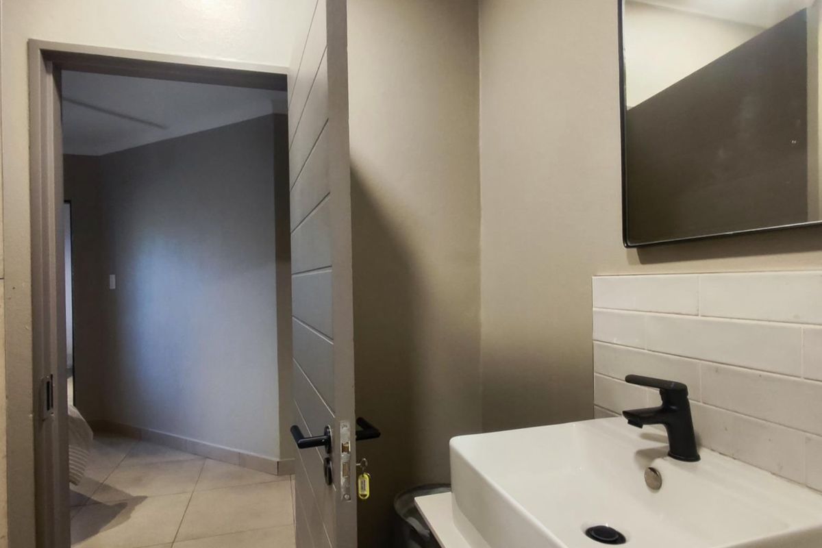 A modern bathroom featuring a vanity basin with a black mixer tap, subway tile splashback, and a wall-mounted mirror.