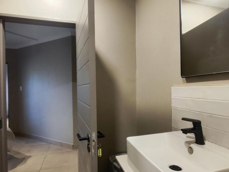 A modern bathroom featuring a vanity basin with a black mixer tap, subway tile splashback, and a wall-mounted mirror.